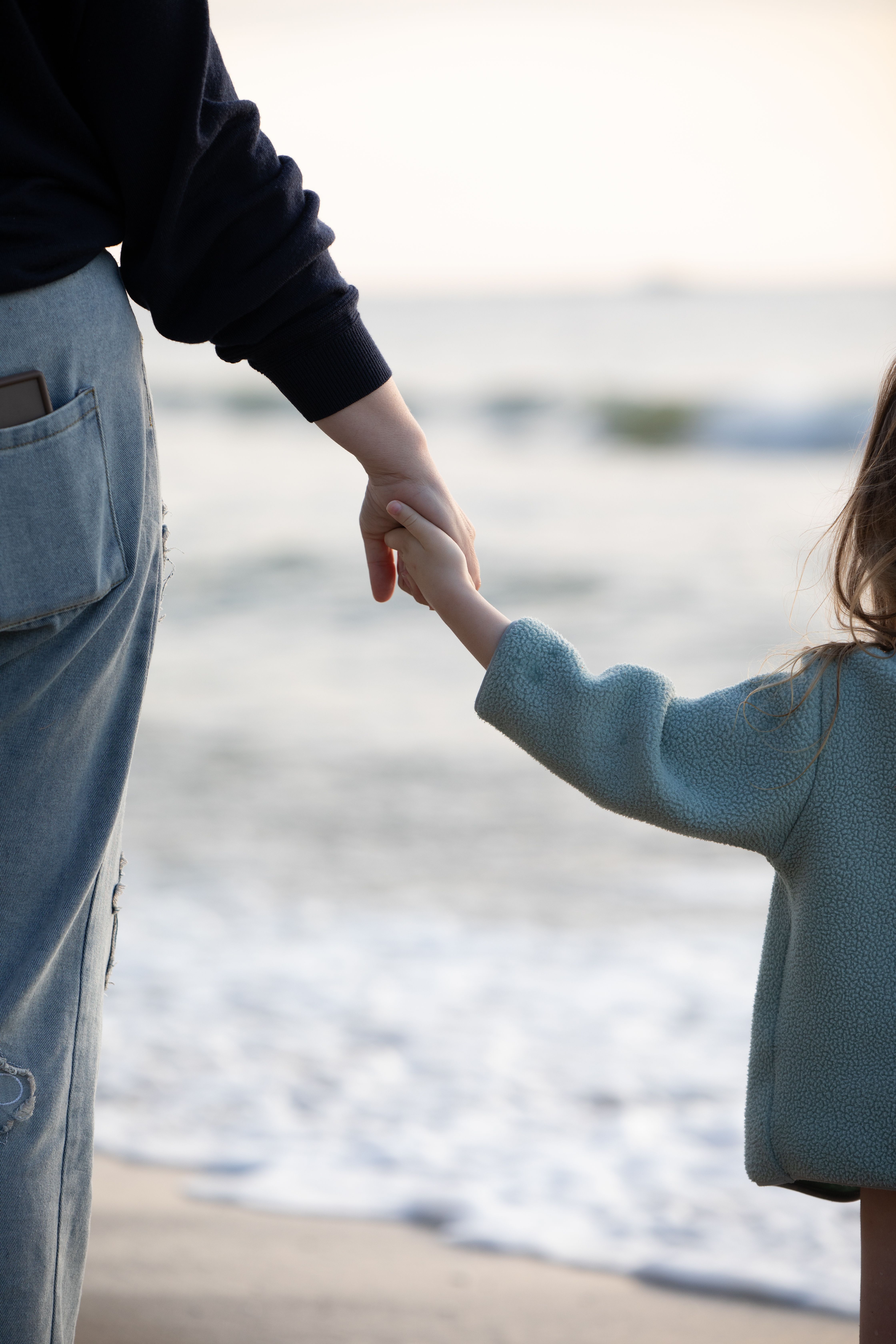 Parent and child holding hands by the water